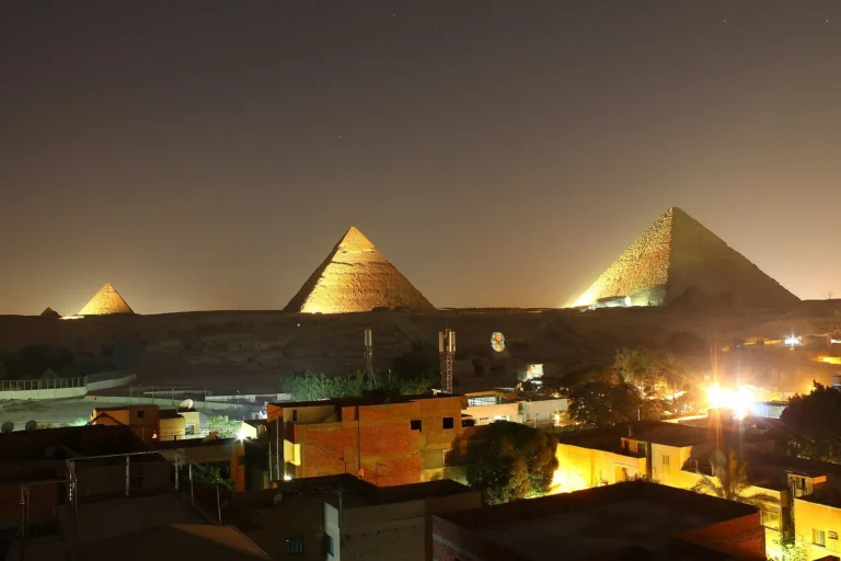 The three pyramids of Giza lit up at night above the city