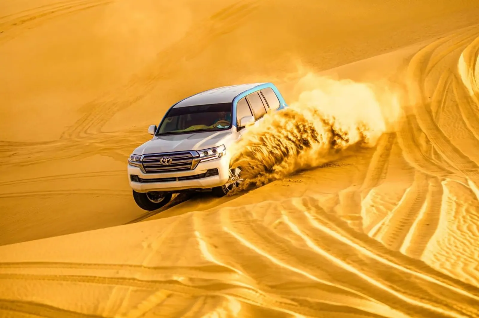 A 4WD kicking up sand at sunset