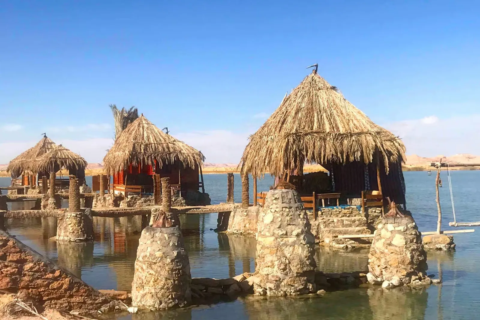 Palm-roofed huts over the water at Fatnas Island