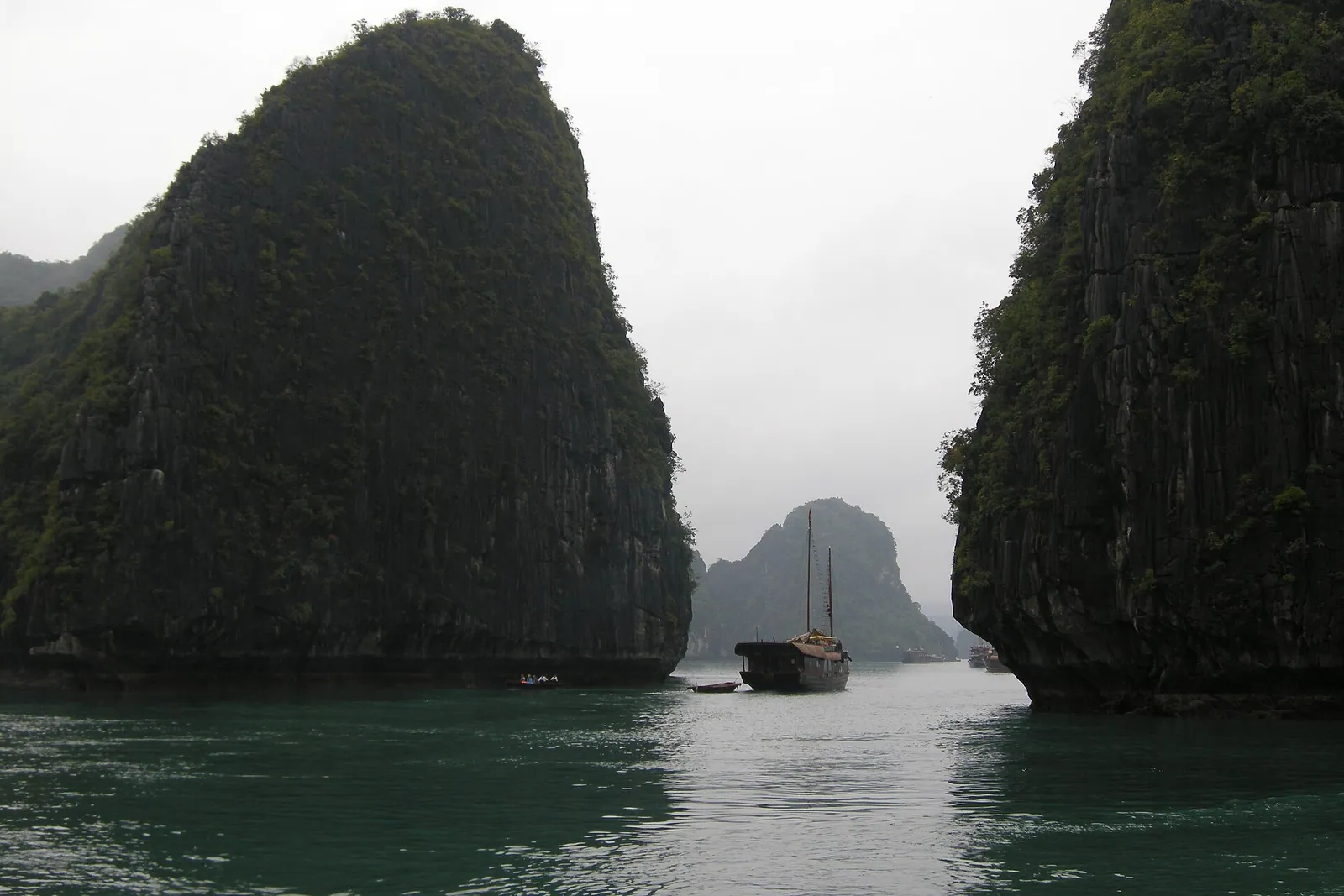 Limestone karst islands and a junk boat in Ha Long Bay, Vietnam